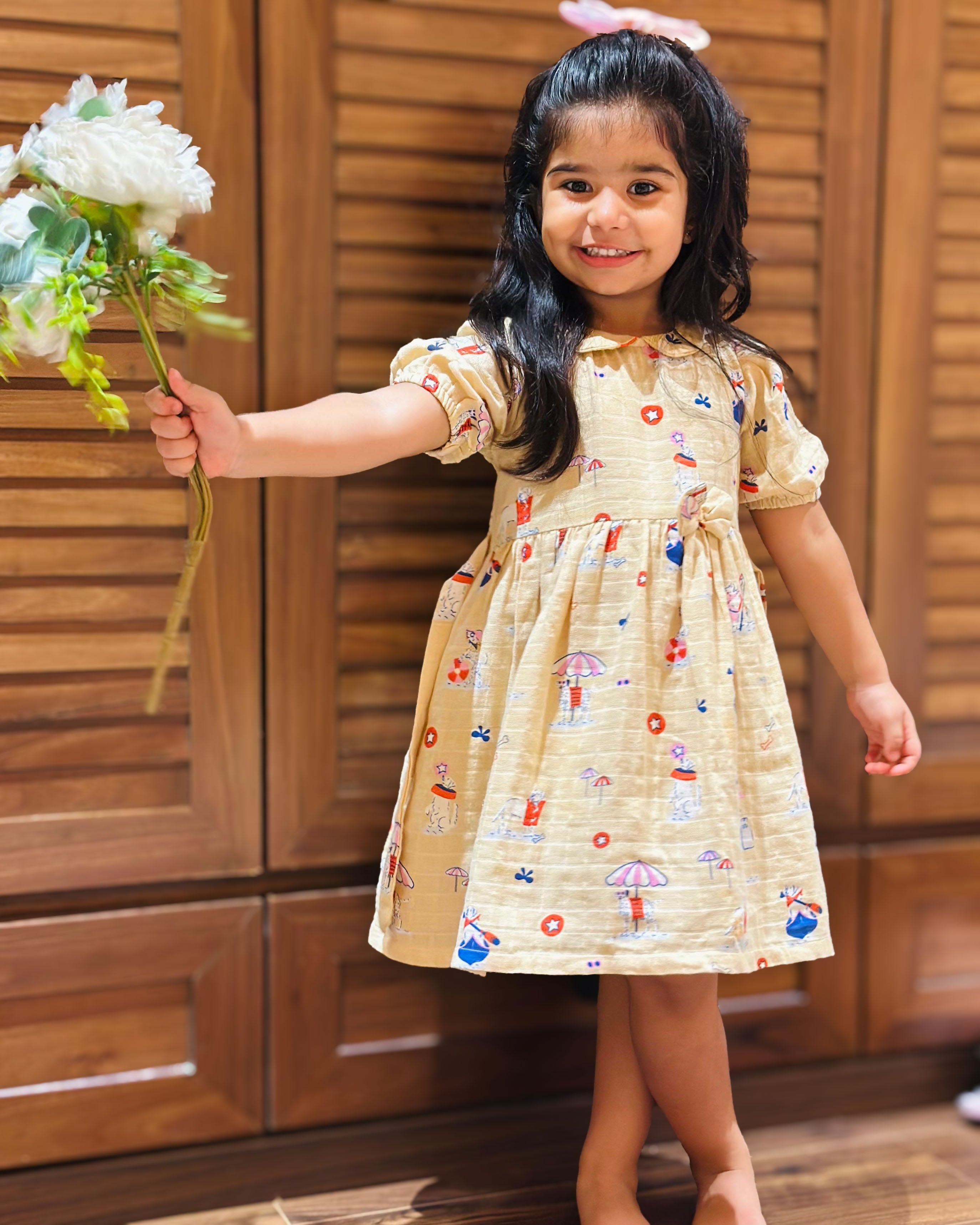 baby girl wearing half sleeve muslin frock with peter pan collar beige and all over print 