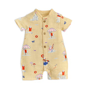 Organic muslin baby romper with dog print at beach- front view showing button closure and short sleeves