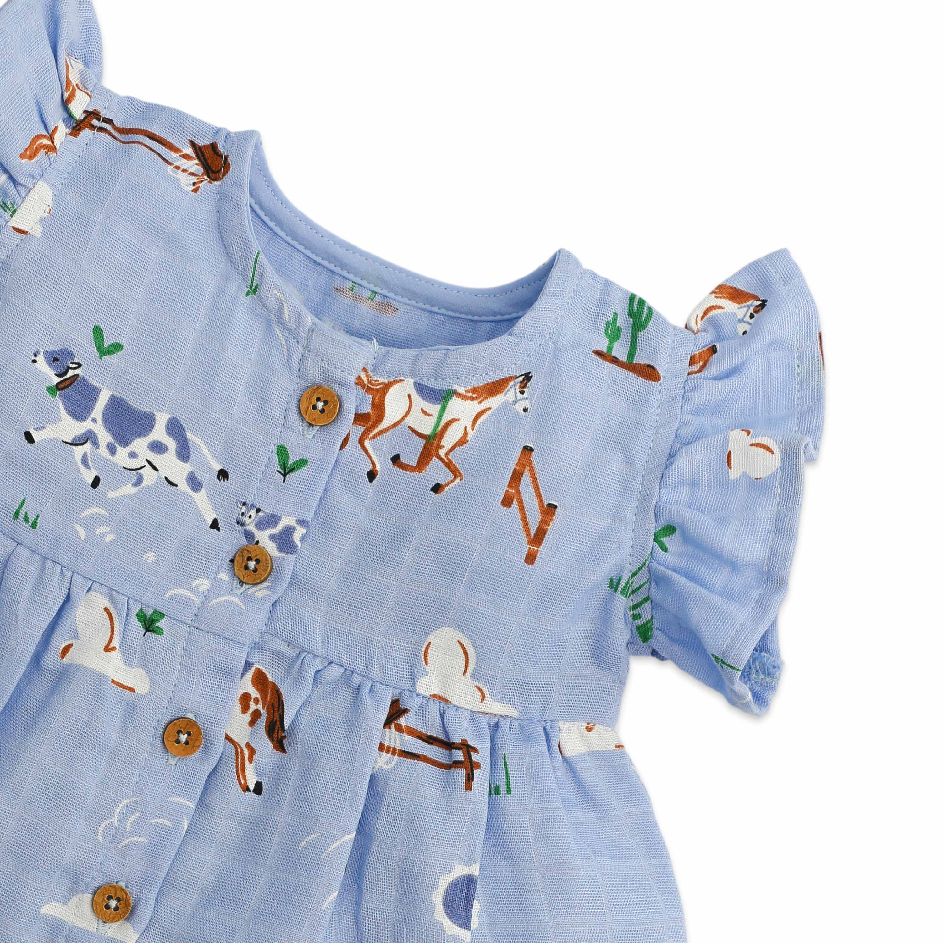 Baby frock detail showing farm animals on light blue muslin fabric with wooden buttons