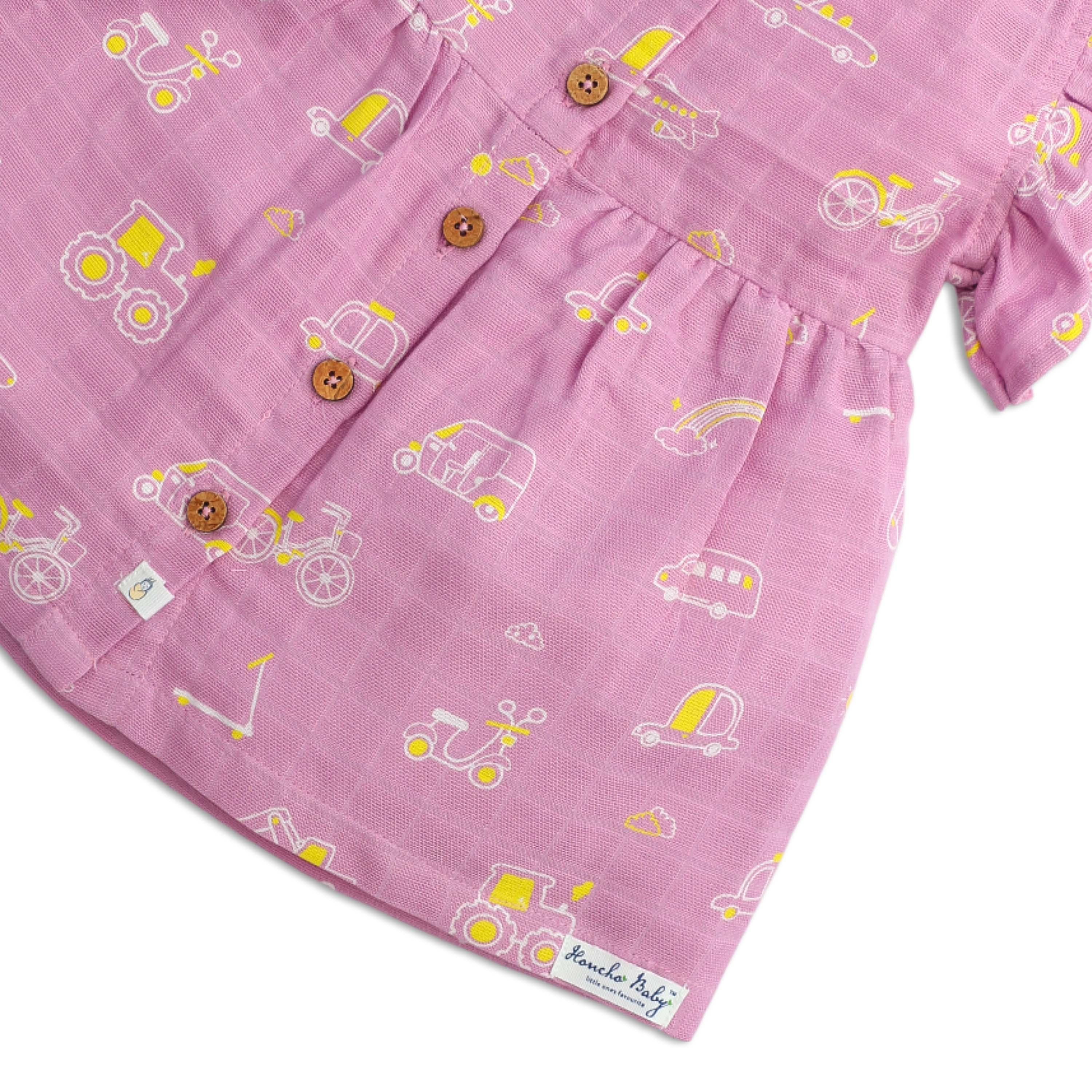 Close-up of coconut shell buttons and soft muslin cotton fabric texture on baby frill sleeve dress with honcho baby brand label